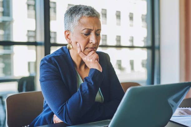 istock Serious, busy and thinking businesswoman working at a computer desk typing reports and looking for project ideas. Mature, ambitious and smart female manager sitting in a corporate startup office 1414393974