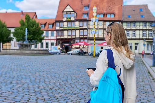 Woman tourist taking photo in an old European city, in front of historical building. Female traveling through Germany using smartphone to take photo. Tourism, history, architecture concept