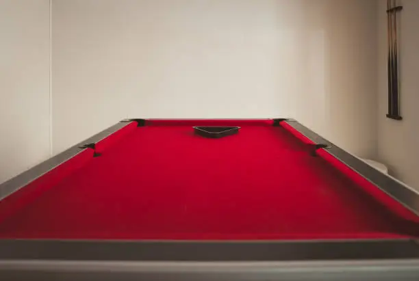 Small side perspective on almost empty red pool table