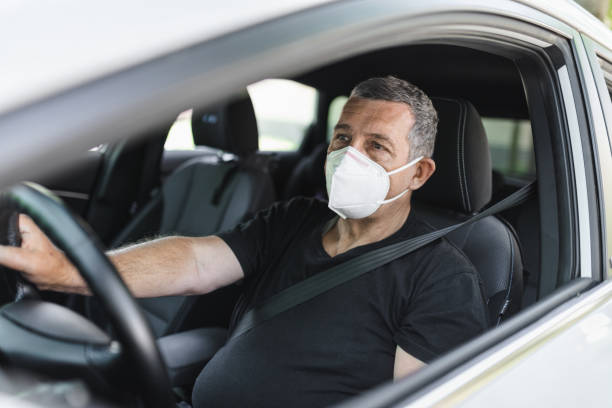 istock Senior in his 70s driving car wearing a face mask 1414402049