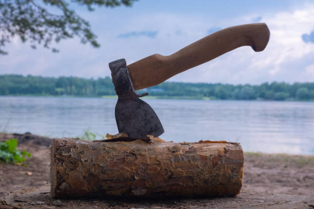 istock Axe in a log against the background of the river and clouds. 1414402485