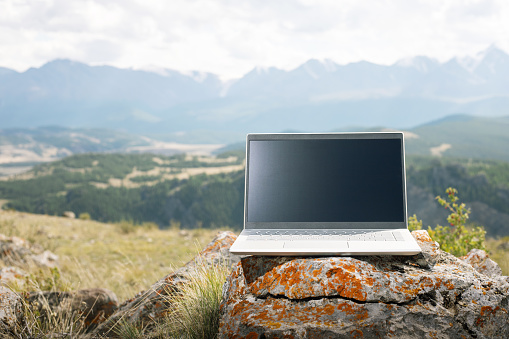 concept of remote work. laptop computer on the  natural stone in mountains.