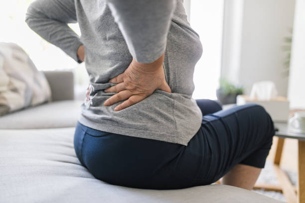 elderly woman at home with back pain - lower back pain imagens e fotografias de stock