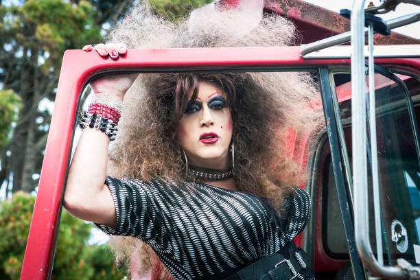 drag queen z wielką peruką stojącą przy starym samochodzie - travesty zdjęcia i obrazy z banku zdjęć