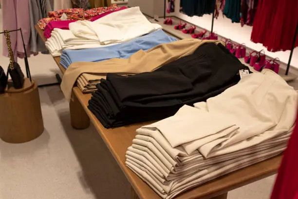 Women's dress pants, stacked in different colors, on a table. Fashion concept.