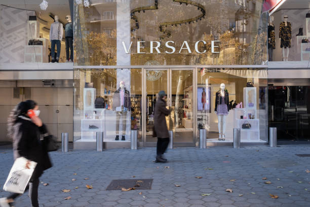 versace modehaus fassade mit schaufensterpuppen ausgestellt. fußgänger, die auf dem bürgersteig laufen. - passeig de gracia stock-fotos und bilder