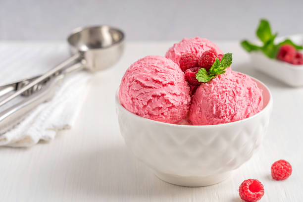 istock Raspberry ice cream or sorbet scoops served in bowl with red berries and mint leaf on white wooden table 1414410893