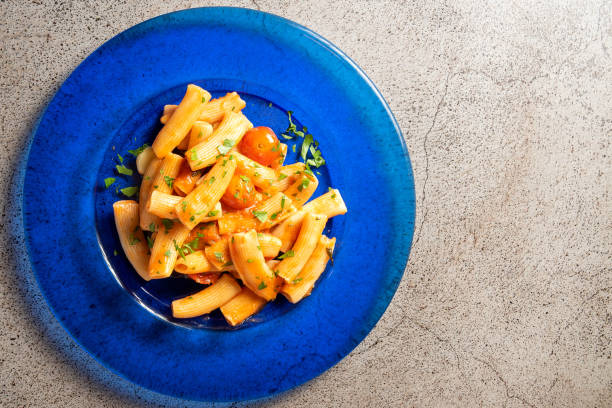 Top view of Rigatoni Arrabiata a traditional Italian dish on a concrete background. Top view of Rigatoni Arrabiata a traditional Italian dish on a concrete background. High quality photo tomato rigatoni stock pictures, royalty-free photos & images