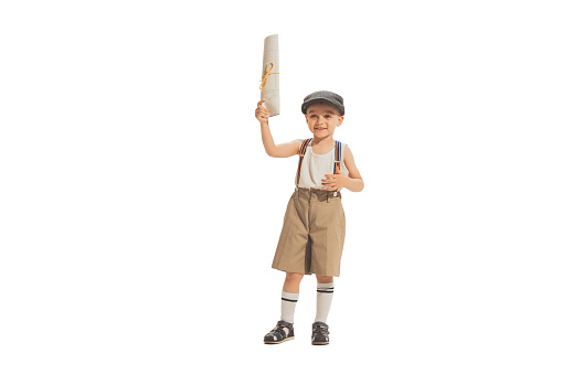Paperboy, newsboy. Cute happy kid in retro style shorts holding newspaper isolated on white studio background. Vintage style concept. Friendship, hobbies, art, eras comparison and children emotions