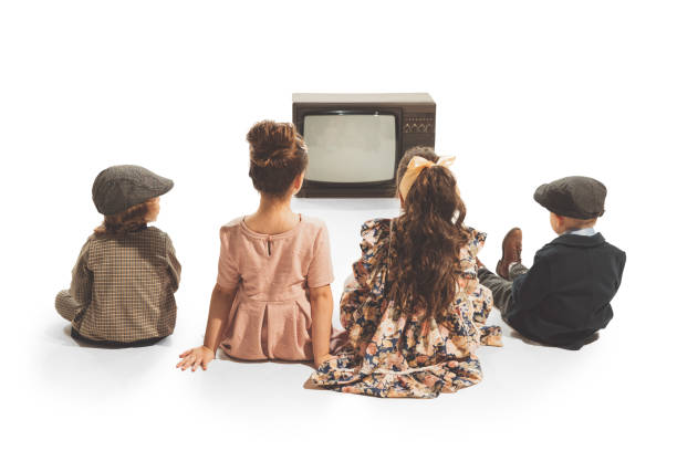 ファッショナブルな子供たちのグループ、白い背景に隔離されたレトロなテレビセットの前に座っている子供たち。ヴィンテージスタイルのコンセプト。友情、趣味、芸術 - colors white art group of objects ストックフォトと画像