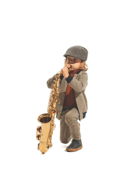 istock Cute happy kid playing saxophone isolated on white studio background. Retro vintage style concept. Friendship, hobbies, art, eras comparison 1414415914