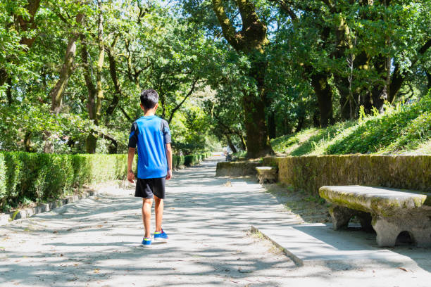istock Child walking alone in a city park on a very sunny day. 1414416708