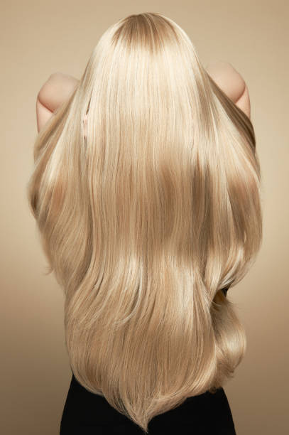 Back view of woman with long beautiful blond hair Back view of woman with long beautiful blond hair isolated on beige background. Dyeing and hair care. Shiny smooth blonde hair woman smooth hair stock pictures, royalty-free photos & images