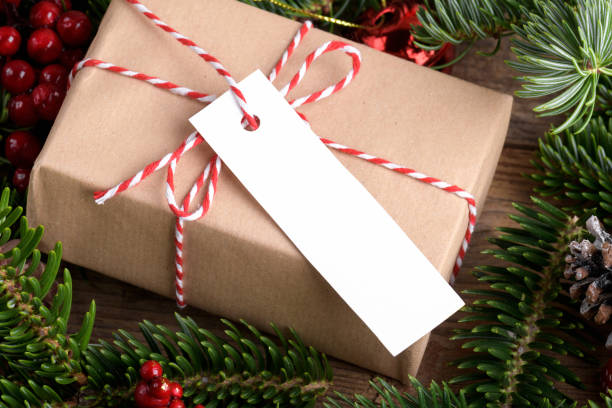 istock Christmas rectangle strip gift tag mockup with present box, product label mockup, with natural fir tree branch, name tag 1414429096