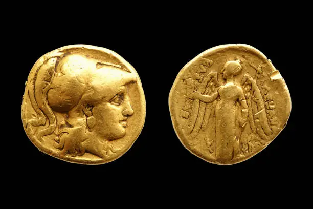 Two sides of an ancient greek gold coin with Alexander the Great isolated on black background.