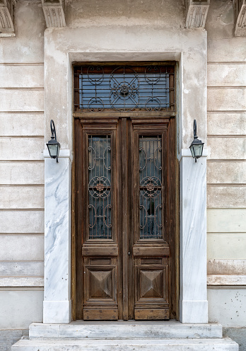 Vintage brown wooden old door in the centre of Athens in Greece. Wooden textured big door with two lights.