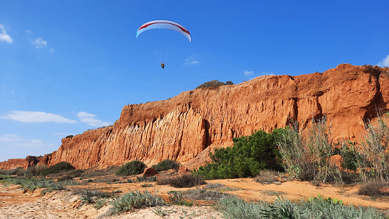 A paraglider above the beach of La Falaise, in Albufeira, Portugal, in the Algarve region
