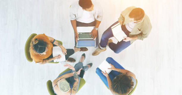 istock Teamwork, talking and meeting group of creative colleagues planning interview, discussing marketing project. Casual business team with books, laptops and paperwork from above 1414434468