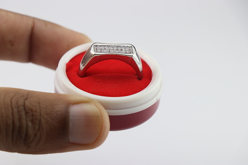 Engagement ring in a box, Silver ring in a small red jewelry box held in hand on white background