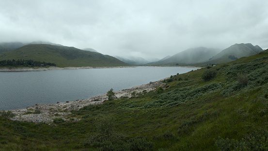 Scottish landscape with lake surrounded by mountains and low clouds. Cluanie Loch. Highlands, Scotland