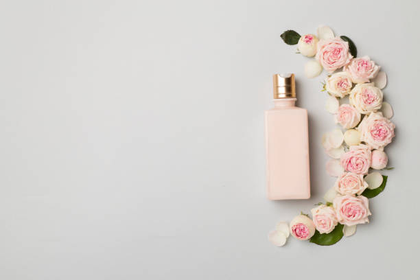 istock Cosmetic bottle with rose flower on color background, top view 1414439094