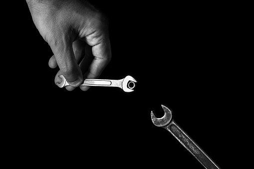 Old wrench in hand on a black background. High quality photo