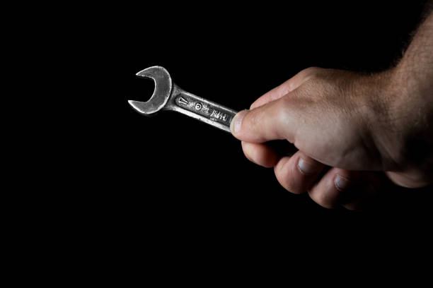 istock Old wrench in hand on a black background 1414439302