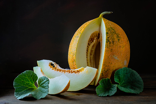 fresh Whole and sliced of Japanese melons, honey melon cantaloupe (Cucumis melo) leaf wooden table background. fruit summer Fruits healthcare concept. dark Food backdround Still Life, squash