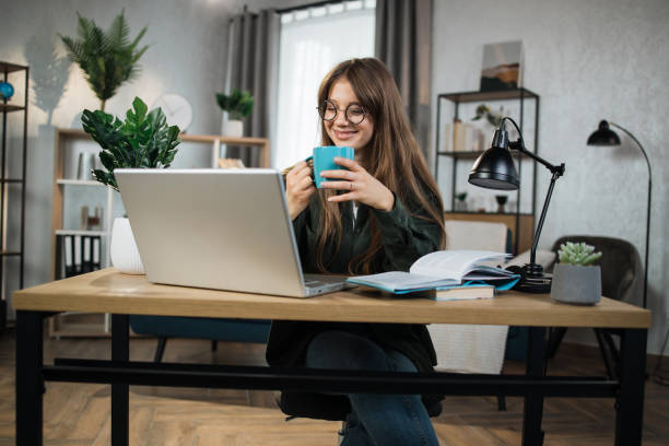 istock Young excited woman sitting at workplace with portable computer and document. 1414440664