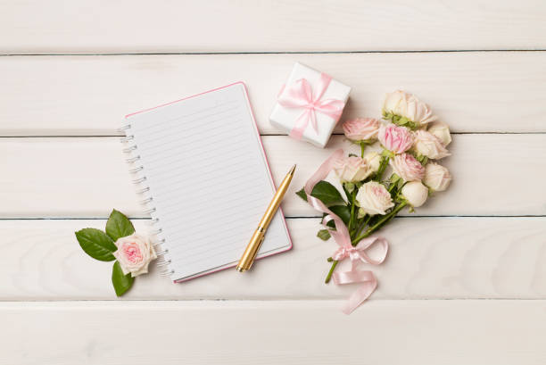 istock Notebook, gift box and rose flowers on wooden background, top view 1414442147