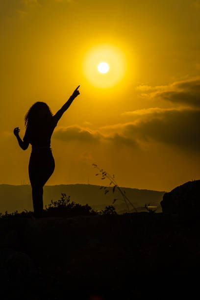 A happy girl pointing to the sun with joy, black shadow object