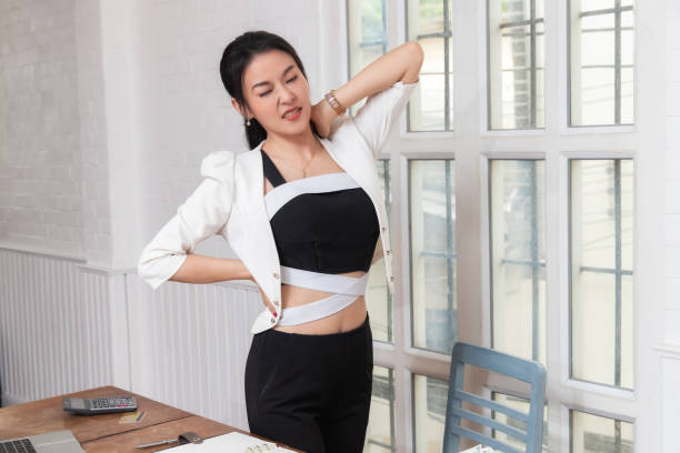 Office syndrome concept. Businesswoman twisting the body to relieve fatigue , suffering from pain after sedentary working in incorrect posture. stock photo
