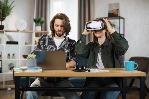 istock Happy young friends sitting at the table and using modern gadgets for work or study. 1414451548