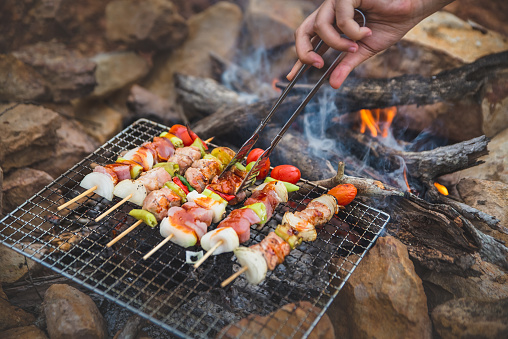 Close up grilling barbecue, BBQ or Steak Meat Roast on natural fire Camping atmosphere. Relaxing time camping on a mountain. Activity in holiday concept.