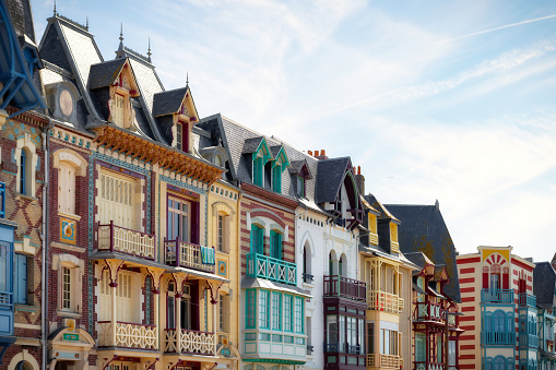 low angle view on multi-colored facades of historic houses alongside the beach promenade in Mers-Les-Bains at the Atlantic coast of France against blue sky