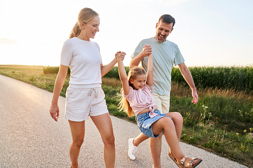 Family of three caucasian people spending time on walking on village road