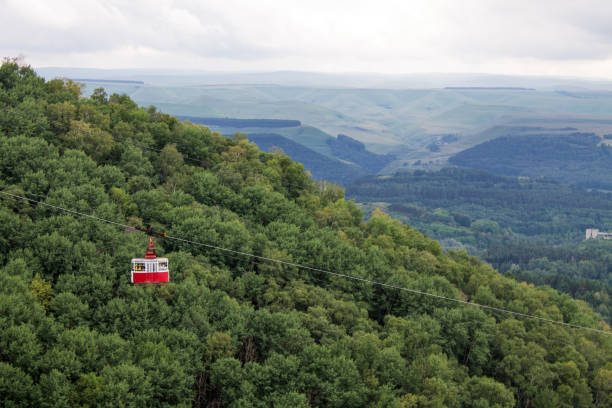 the cab of the funicular rises on a cable rope against the background of a wooded mountain slope - blurred motion street car green imagens e fotografias de stock