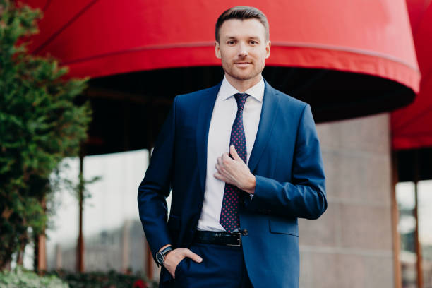 istock Handsome male company owner dressed formally, stands outside, has confident expression, ready for business meeting. Successful young attractive executive manager poses outdoor near office building 1414459814