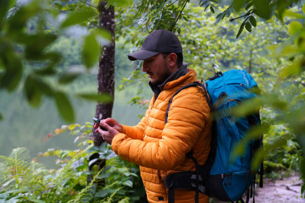 istock Man walking alone in the woods looking for direction on phone, 4K resolution 1414463223
