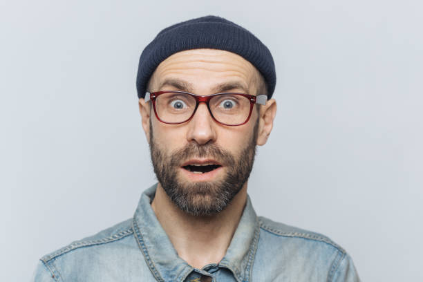 istock Horizontal shot of amazed excited shocked man stares at camera with unexpected expression, keeps mouth opened, hears awful news, isolated over grey background. Omg and great surprisment concept 1414464566