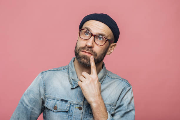 istock Thoughtful bearded male being deep in thoughts, looks with pensive expression into camera, concentrated on something, poses against pink background. People, facial expressions, daydreaming concept 1414464608