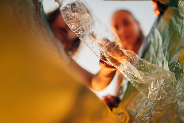 istock Mother and daughter throw plastic bottles into plastic garbage bag 1414465841