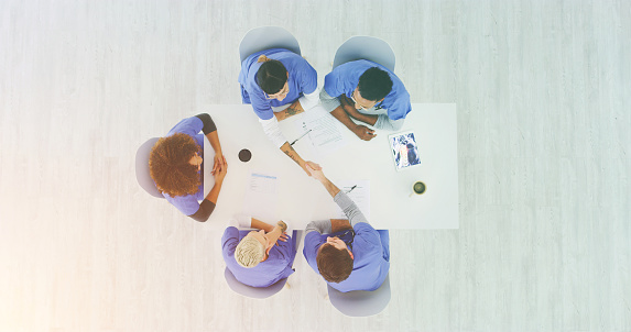 Doctors handshake at team meeting for medical breakthrough success, promotion or welcoming a healthcare worker. Shaking hands for promotion, achievement or recognition in medical research from above