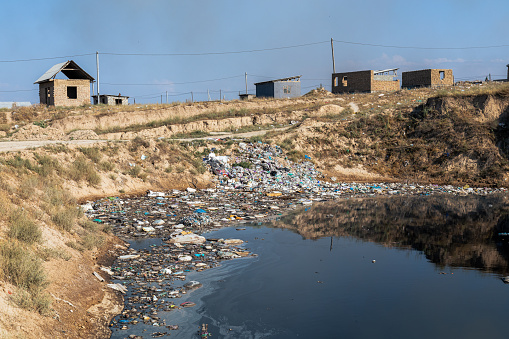 Toxic pond with trash near burning landfill piles
