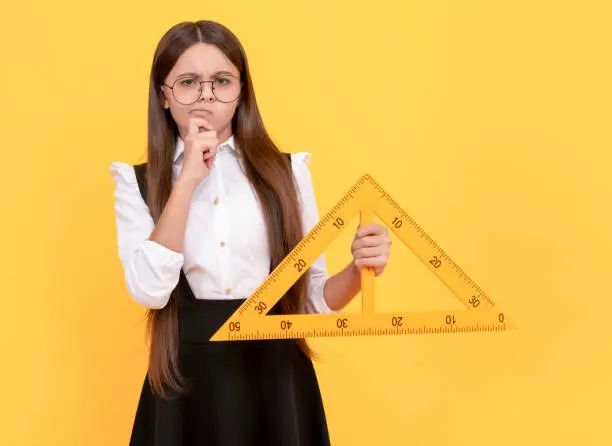 thinking teen girl in school uniform and glasses hold mathematics triangle for measuring, measurement.