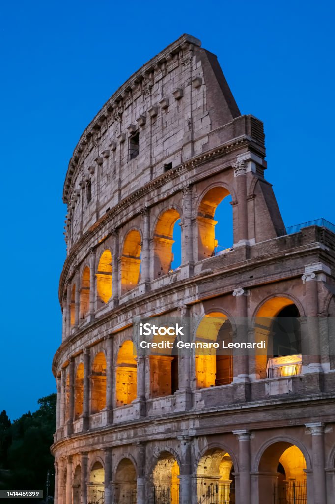 Colosseum illuminated in the evening. Side view of the facade of the Colosseum at dusk, with the illuminated arches. Coliseum - Rome Stock Photo