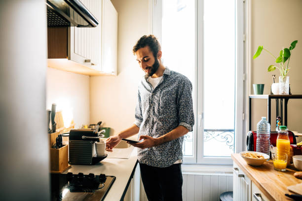 istock Middle Eastern man preparing coffee on coffee machine in modern kitchen and using smart phone 1414471052