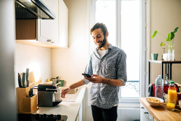 istock Middle Eastern man preparing coffee on coffee machine in modern kitchen and using smart phone 1414471122
