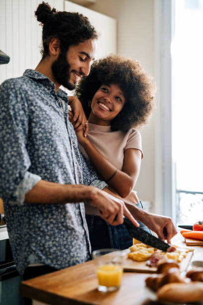 apasionada pareja multiétnica en la cocina preparando comida y divirtiéndose - bonding vertical men women fotografías e imágenes de stock