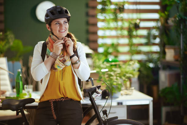 smiling trendy business woman in bike helmet in eco office stock photo